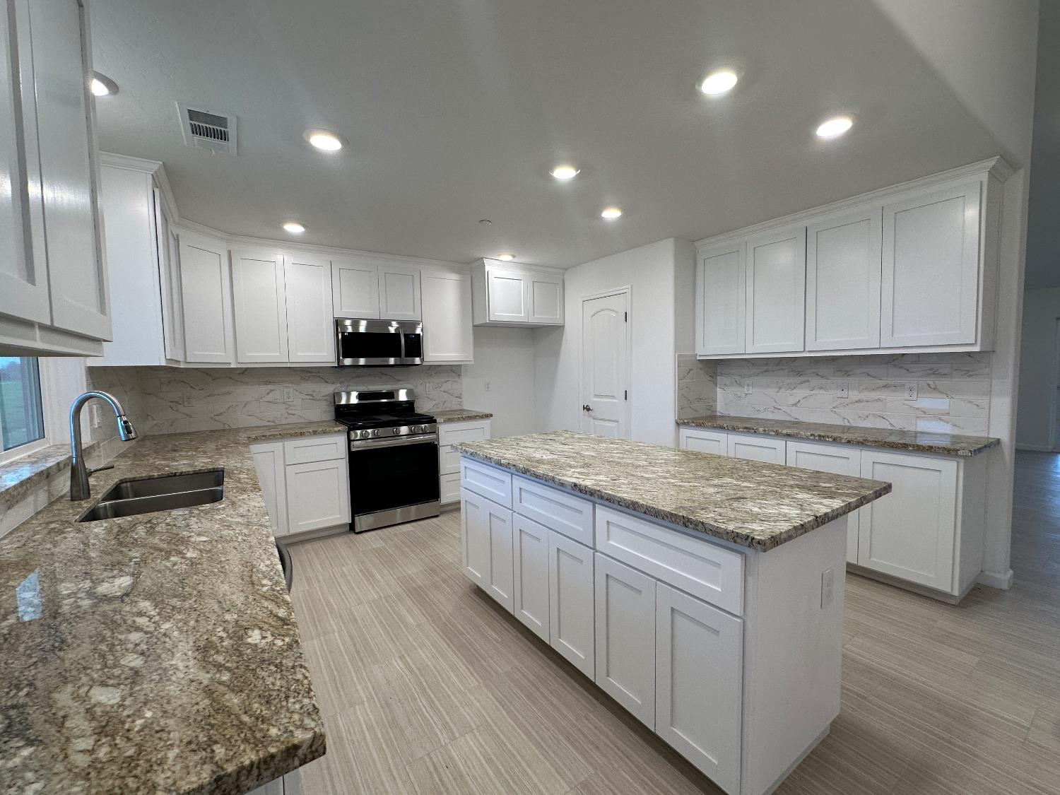20568 Road 31 Madera, CA 93638 - Photo 4 of 24 a kitchen with granite countertop sink stove and cabinets