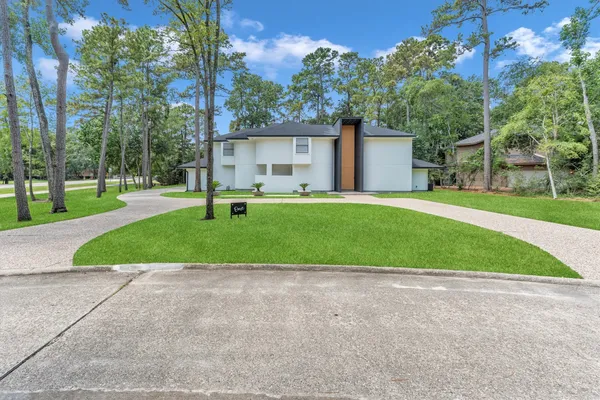 a view of a house with a big yard and large trees