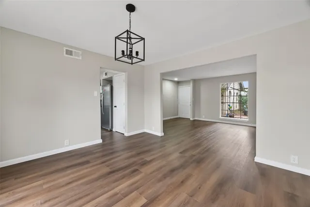 a view of an empty room with window and wooden floor