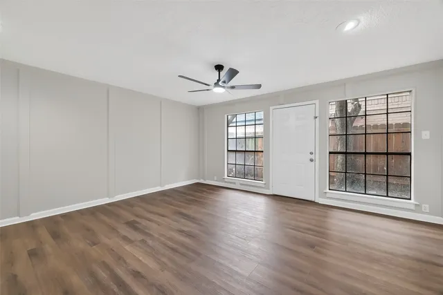 a view of an empty room with a window and wooden floor
