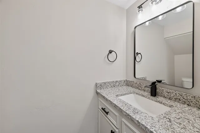 a bathroom with a granite countertop sink and a mirror
