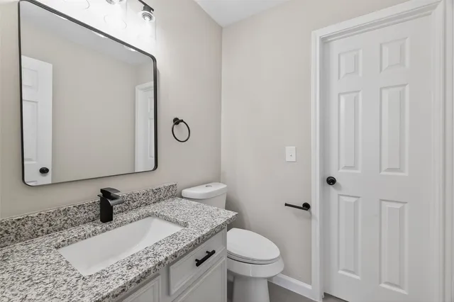 a bathroom with a granite countertop sink toilet and mirror