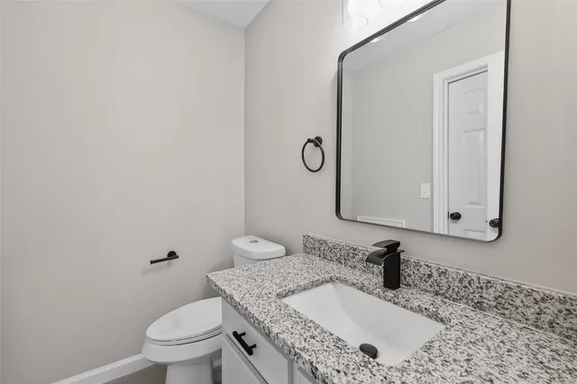 a bathroom with a granite countertop sink a toilet and a mirror
