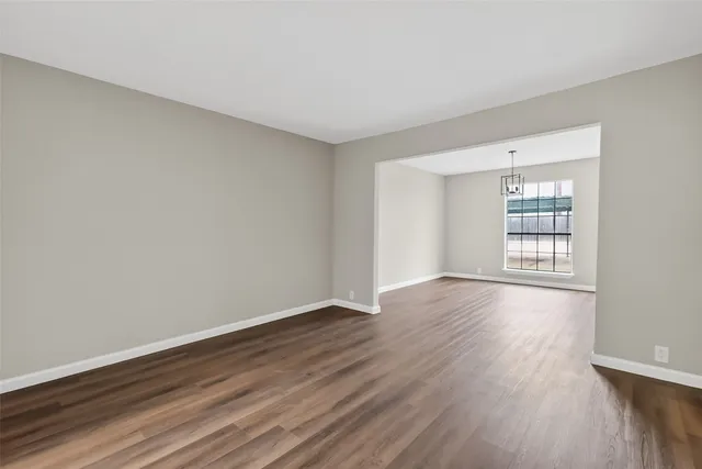 a view of an empty room with wooden floor and window