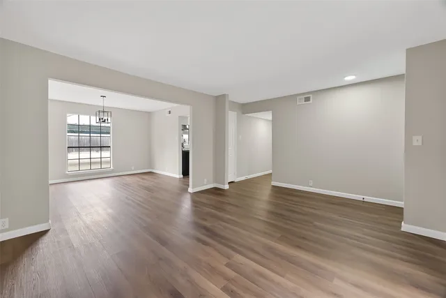 a view of an empty room with wooden floor and windows