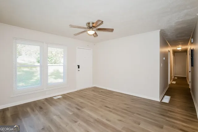 a view of an empty room with wooden floor and a window