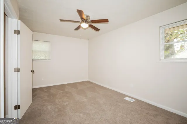 an empty room with closet and a ceiling fan