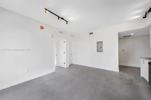 an empty room with windows and ceiling fan