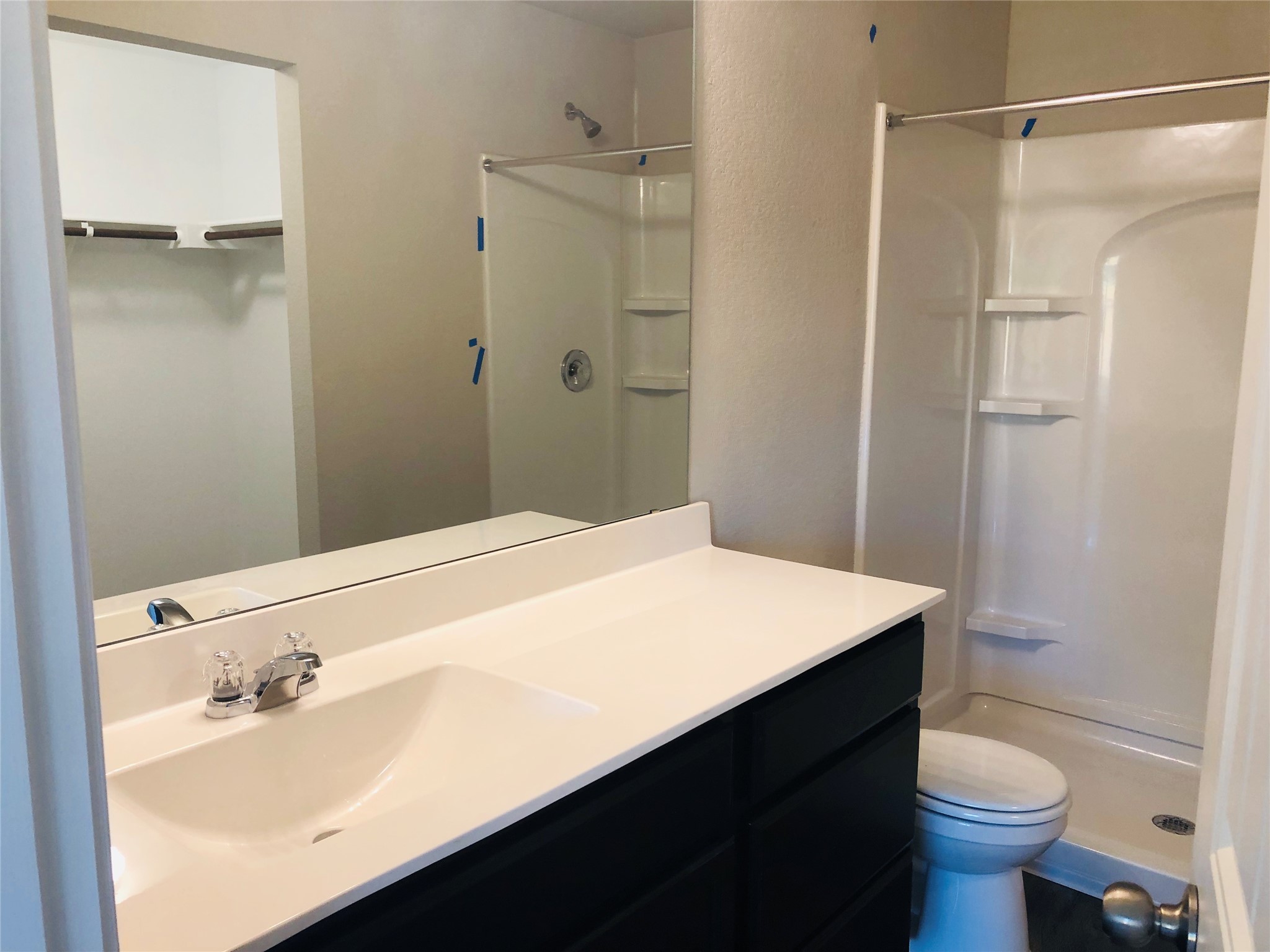 5712 Ronee Leah Drive Austin, TX 78724 - Photo 12 of 14 Bathroom featuring a vanity with a white countertop, a sink with chrome fixtures, a mirror, and a shower with built-in shelving