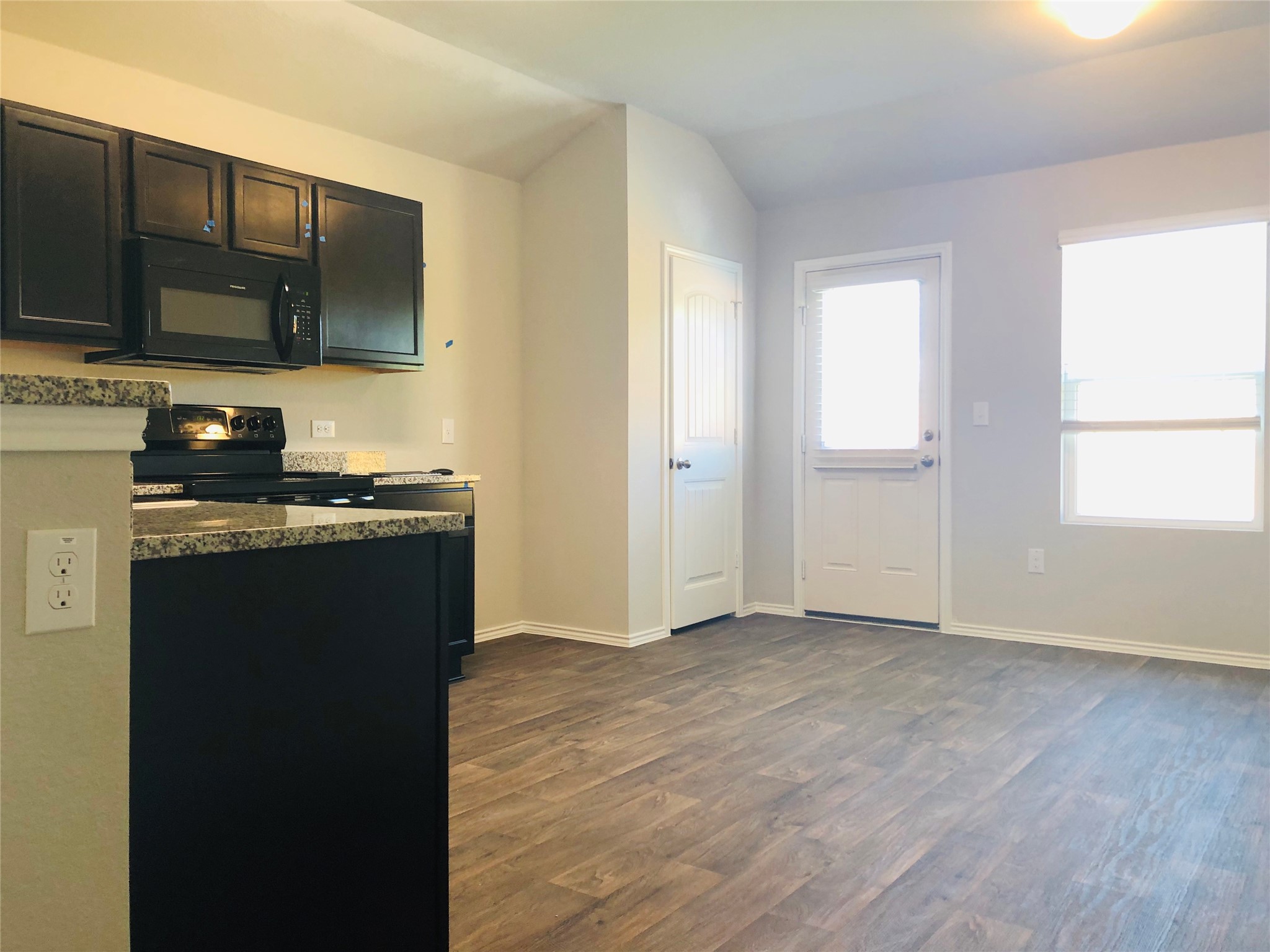 5712 Ronee Leah Drive Austin, TX 78724 - Photo 6 of 14 The kitchen features dark cabinetry, granite countertops, and black appliances including a microwave and range
