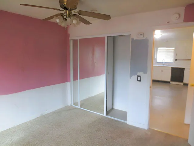 an empty room with fan and windows