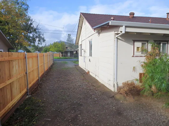 a view of a house with a small yard and wooden fence