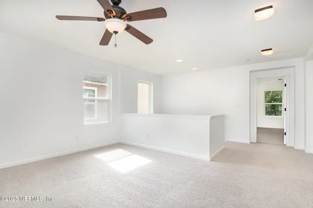an empty room with chandelier fan and windows