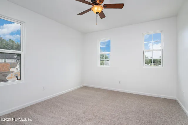 an empty room with a window and a fan