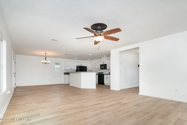 an empty room with wooden floor and ceiling fan