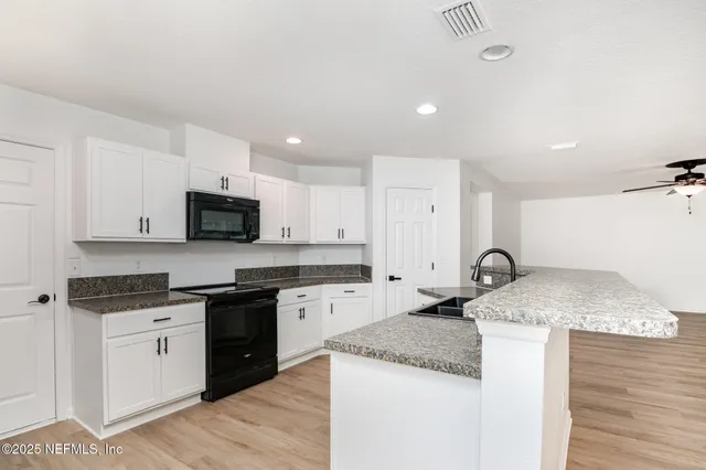 a kitchen with granite countertop a sink a stove and wooden cabinets