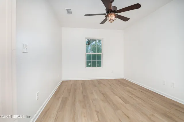 an empty room with a window and a ceiling fan