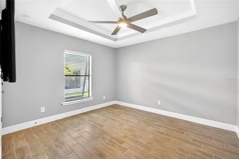 an empty room with wooden floor fan and windows
