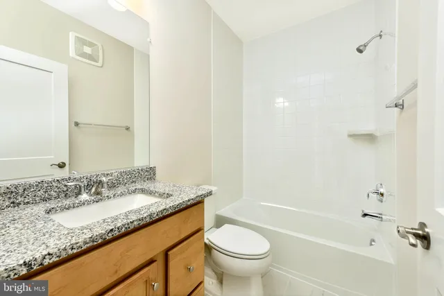 a bathroom with a granite countertop sink a toilet and bathtub