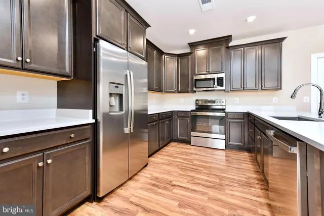 a kitchen with stainless steel appliances granite countertop a refrigerator a sink a stove and oven