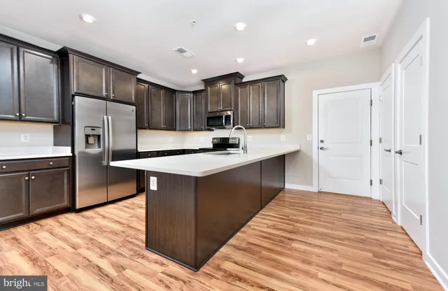 a kitchen with kitchen island a counter top space cabinets and stainless steel appliances