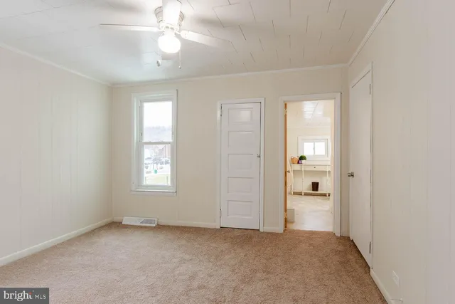 an empty room with windows and fan