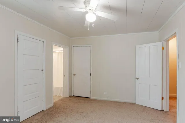 an empty room with closet and a ceiling fan