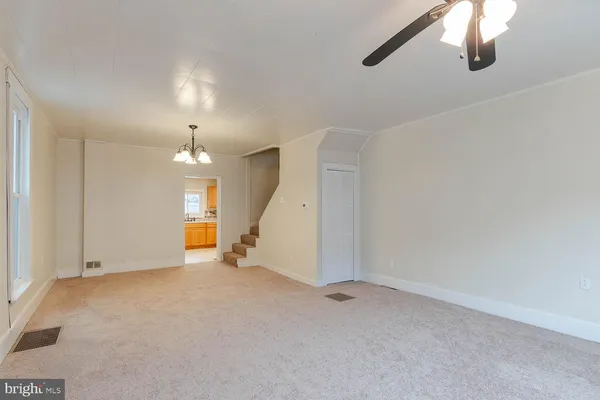 an empty room with chandelier fan and windows