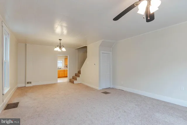 an empty room with chandelier fan and windows