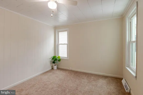 an empty room with windows and chandelier fan