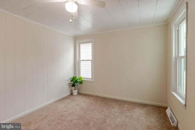 an empty room with windows and chandelier fan