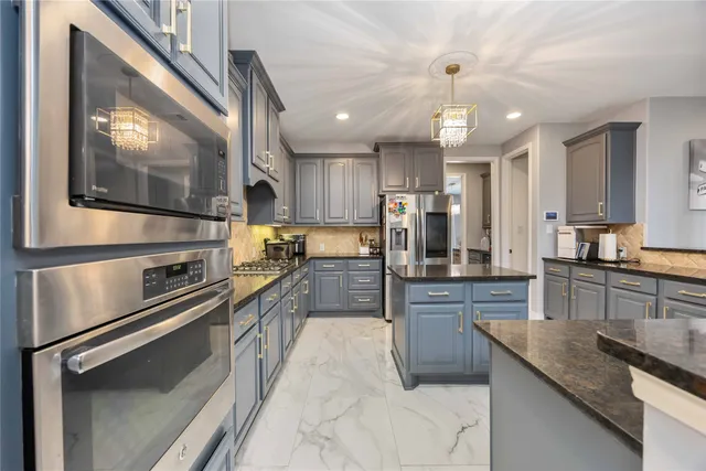 a kitchen with stainless steel appliances granite countertop a refrigerator a stove and a sink with wooden floor