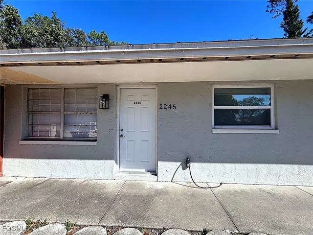 a white house with tall trees in the background