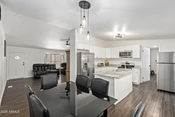 a kitchen with stainless steel appliances kitchen island granite countertop a refrigerator a stove top oven a sink dishwasher and white cabinets