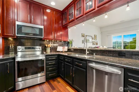 a kitchen with stainless steel appliances granite countertop a stove a microwave and wooden cabinets