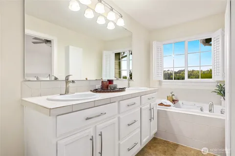 a bathroom with a sink vanity granite tub and a mirror