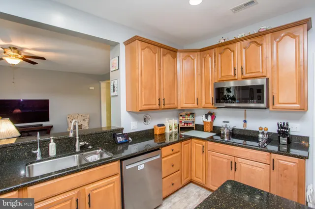a kitchen with stainless steel appliances granite countertop a sink a stove a microwave cabinets and a window