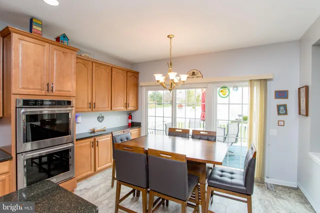 a kitchen with stainless steel appliances granite countertop a stove top oven a sink a dining table and chairs with wooden floor