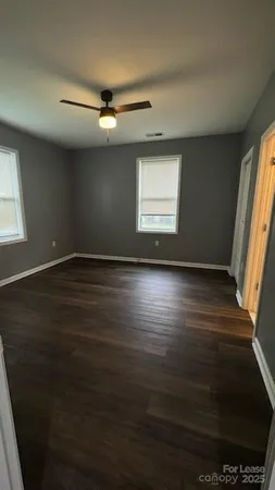 an empty room with wooden floor fan and windows