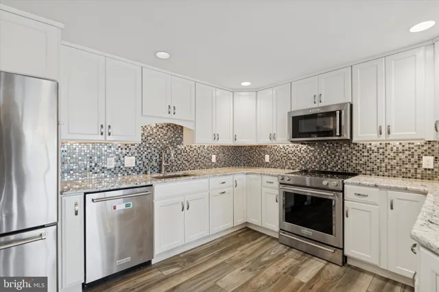 a kitchen with granite countertop white cabinets white stainless steel appliances and granite counter tops