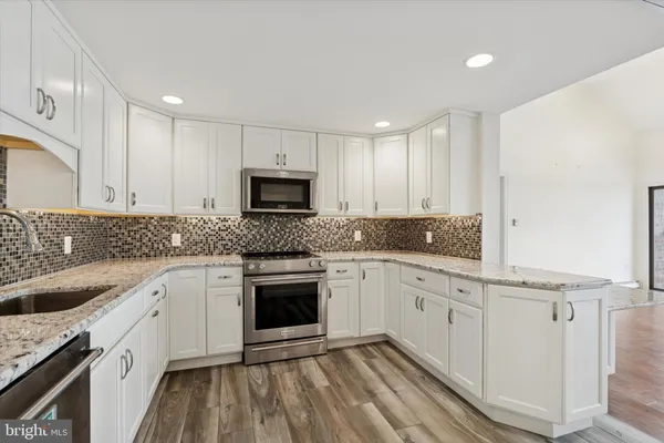 a kitchen with granite countertop white cabinets white stainless steel appliances with a sink and dishwasher