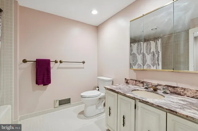 a bathroom with a granite countertop sink a toilet and a shower