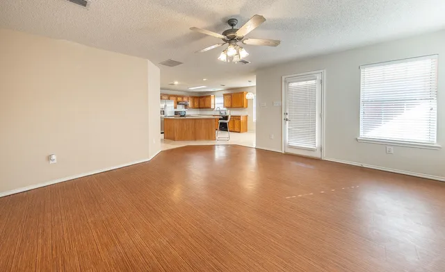 a view of an empty room with a window and wooden floor