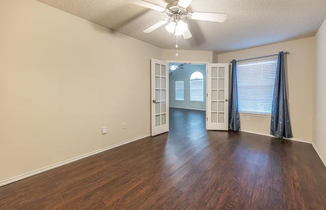an empty room with wooden floor and a ceiling fan