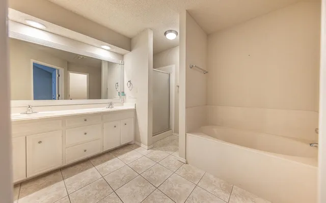 a spacious bathroom with a double vanity sink a mirror and a bathtub