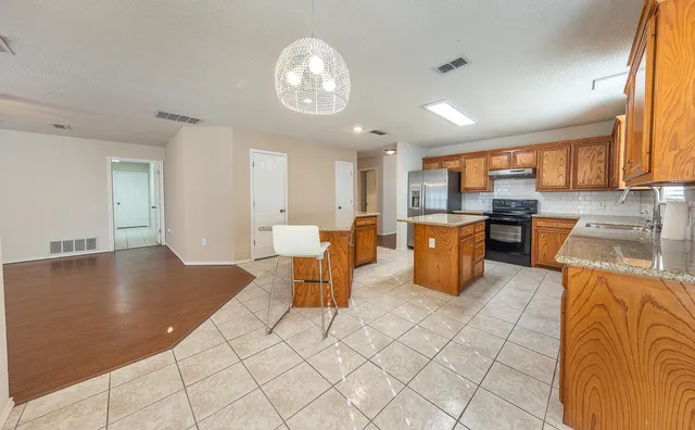 a open kitchen with stainless steel appliances granite countertop a stove top oven a dining table and chairs with wooden floor