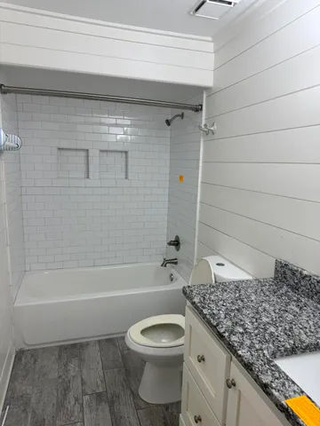 a bathroom with a granite countertop toilet a sink and bathtub
