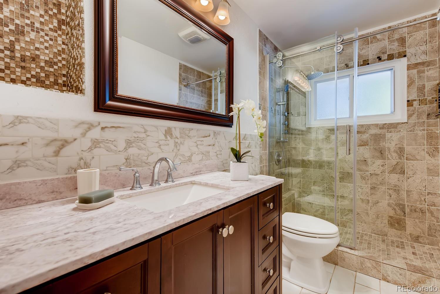 2621 Paseo Road Colorado Springs, CO 80907 - Photo 15 of 27 a bathroom with a granite countertop sink a toilet and mirror