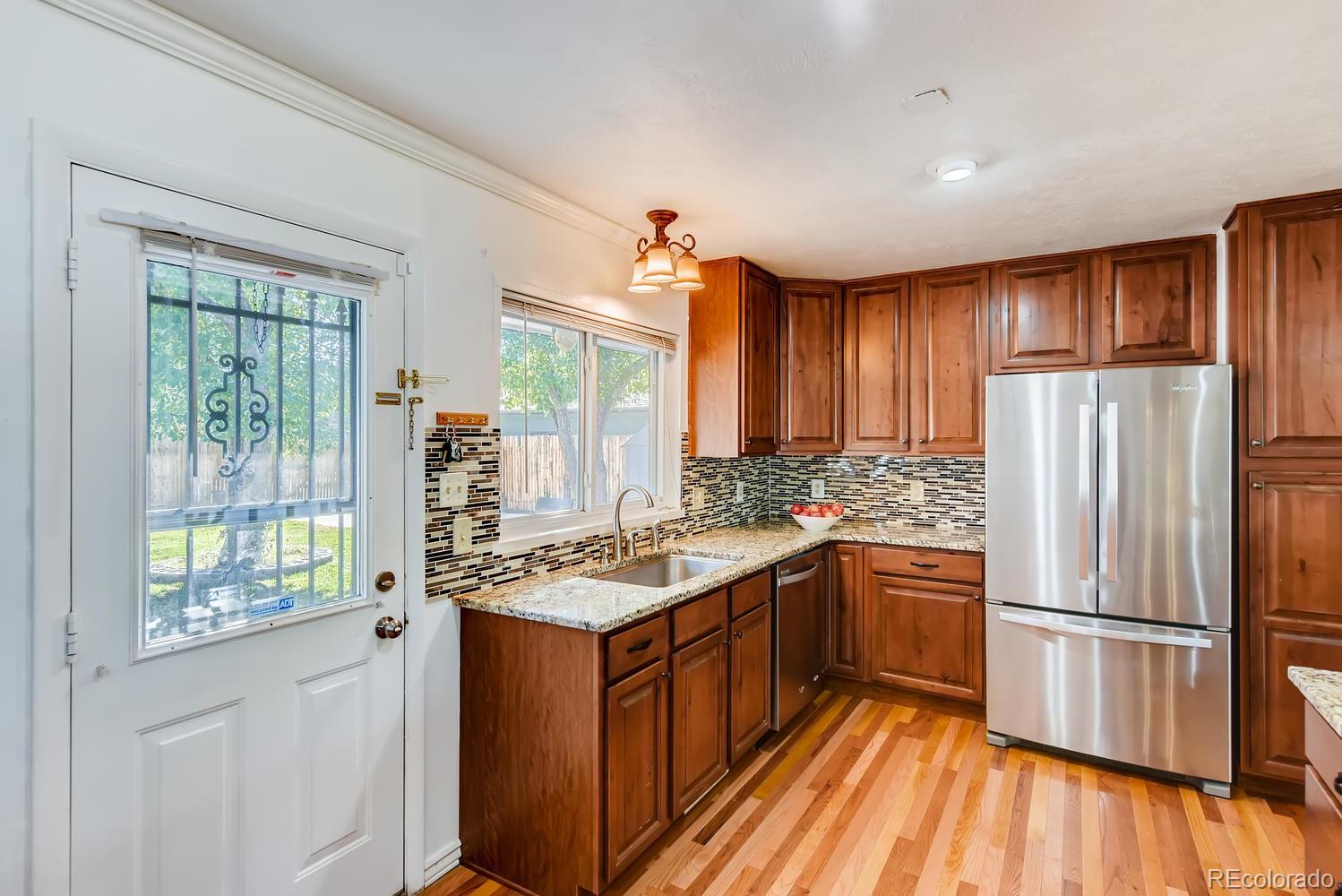 2621 Paseo Road Colorado Springs, CO 80907 - Photo 8 of 27 a kitchen with stainless steel appliances granite countertop a refrigerator a sink dishwasher a stove and white countertops with wooden floor