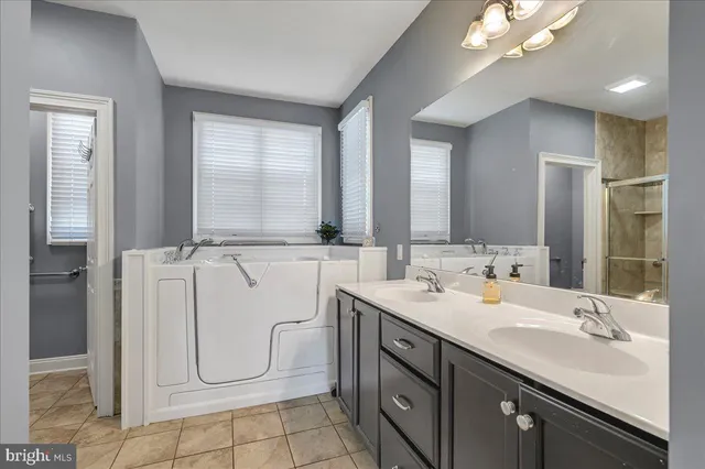 a bathroom with a double vanity sink a mirror and a bathtub